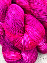 Close-up of bright pink yarn skeins on a textured surface